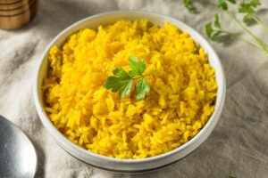 Bowl of cooked turmeric rice with parsley on top for garnish